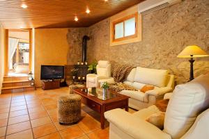 una sala de estar con muebles blancos y una pared de piedra. en Villa Magdalena, en Calviá