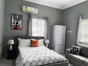 a bedroom with a bed with an orange pillow and a couch at Nuels Apartment in Pokuase