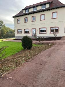 een groot wit huis met rode ramen en een oprit bij Gîte La perle d’Alsace in Bernardswiller