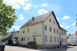 un edificio bianco con un tetto nero su una strada di Gasthaus zum Ritter a Karlsdorf-Neuthard