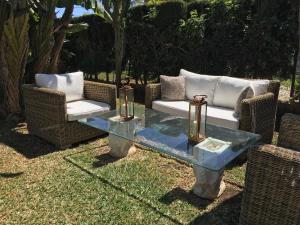 2 chaises en osier et une table en verre dans la cour dans l'établissement Las Gitanillas, villa with heated pool, La Cala de Mijas, à Mijas