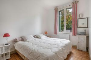 a white bedroom with a large bed and a window at Charmante maison à 250 mètres de la plage in Le Pouliguen