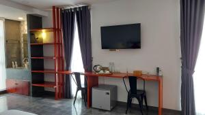 a room with a desk with two chairs and a television at Sok Hotel And Coffee Siem Reap in Siem Reap