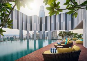 Pan Pacific Serviced Suites Kuala Lumpur في كوالالمبور: مسبح الفندق مع الكراسي وإطلالة على المدينة