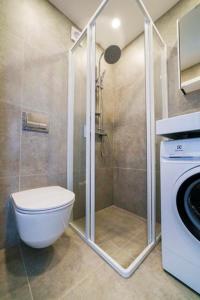 a bathroom with a shower with a toilet and a washing machine at Stylish Studio in Central Vilnius in Vilnius
