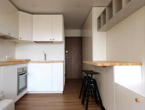 a kitchen with white cabinets and bar stools in it at Stylish Studio in Central Vilnius in Vilnius