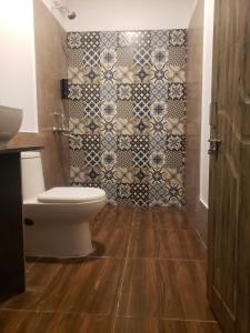 a bathroom with a toilet and a tiled wall at White Truffle Resort, Arambol in Arambol