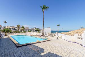 uma piscina com uma palmeira e o oceano em 11 House in front of the sea em Mijas Costa