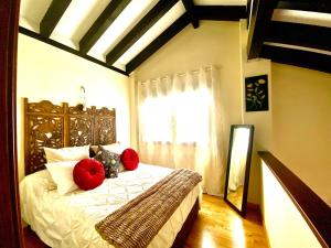 a bedroom with a bed with red pillows and a window at Casita rural Sierra de Sevilla, combina una maravilla in Seville