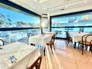 un restaurante con mesas, sillas y ventanas grandes en Hotel Venere en Cesenatico