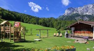 un gran patio con un parque infantil y una montaña en Ferienwohnung Lippenlehen, en Marktschellenberg