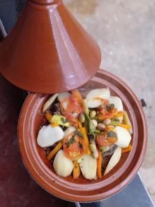 a red bowl of food with tomatoes and vegetables at Assounfou in Ouarzazate