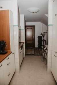 eine Küche mit weißen Schränken und einen Flur mit einer Tür in der Unterkunft Słoneczny Zakątek Krynica-Zdrój in Krynica-Zdrój