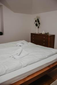 1 cama con sábanas blancas y cómoda de madera en Słoneczny Zakątek Krynica-Zdrój, en Krynica-Zdrój