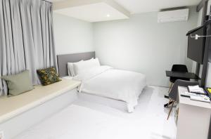 釜山にあるHOTEL LENITH Seomyeonのベッドとデスクが備わる小さな白い客室です。