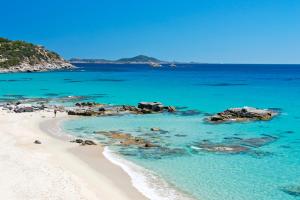 una spiaggia con acqua blu e rocce nell'oceano di Apartments in residence with swimming pool in Villasimius a Villasimius