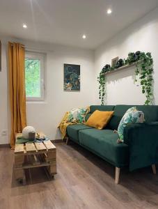 salon z zieloną kanapą i stołem w obiekcie Charmant chalet jungle avec balneo w mieście Arthon