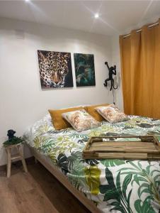 sypialnia z łóżkiem z obrazami na ścianie w obiekcie Charmant chalet jungle avec balneo w mieście Arthon