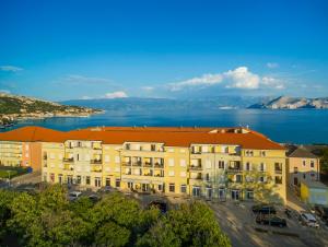 巴斯卡Valamar Atrium Residence的一座有橙色屋顶的建筑,毗邻水体