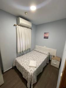 Habitación pequeña con cama y ventana en Hostal Tres Hermanos en Getafe