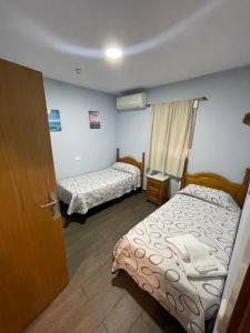 a small room with two beds and a door at Hostal Tres Hermanos in Getafe