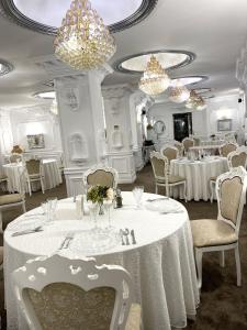 a dining room with white tables and chairs and chandeliers at President in Ploieşti