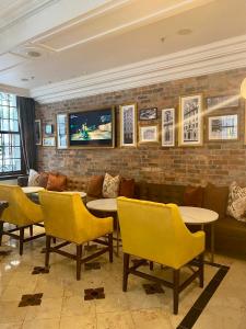 a restaurant with yellow chairs and tables and a brick wall at Taj HotelApart, Taj Hotel Cape Town in Cape Town