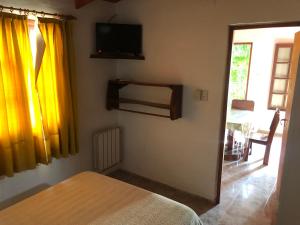 1 dormitorio con 1 cama y TV en la pared en Cabañas Los Aromos en Embalse