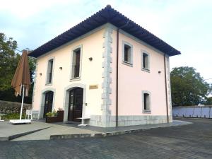 un edificio blanco con una puerta negra y una sombrilla en Hotel Villa Marrón, en Naves