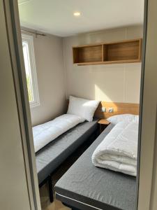 a small room with two beds and a window at Mobil home 6/8 personnes aux Mathes / La Palmyre in Les Mathes
