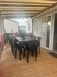 a black dining table and chairs on a patio at Mobil home 6/8 personnes aux Mathes / La Palmyre in Les Mathes