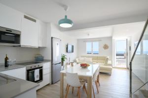 cocina y sala de estar con mesa blanca y sillas en Casa Roman en Punta de Mujeres