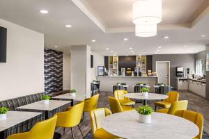 多瓦爾的住宿－Microtel Inn & Suites Montreal Airport-Dorval QC，一间带桌子和黄色椅子的餐厅
