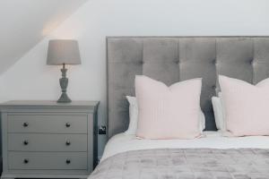 a bedroom with a bed with white pillows and a lamp at The Woodpecker - 1 Bedroom Annexe in Harpsden