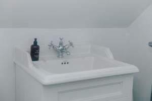a white bathroom sink with a bottle of wine on it at The Woodpecker - 1 Bedroom Annexe in Harpsden