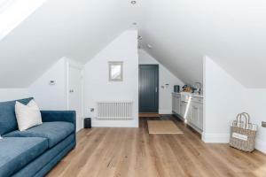 a living room with a blue couch and a kitchen at The Woodpecker - 1 Bedroom Annexe in Harpsden