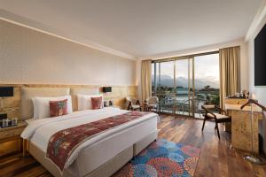 ダラムシャーラーにあるINFINITEA CENTRIC DHARAMSHALAの大きなベッドと大きな窓が備わるホテルルームです。