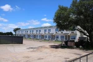 a large white building with a tree in front of it at Days Inn by Wyndham Waco University Area in Waco