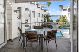 balcón con mesa, sillas y vistas al agua en The Waterfront - Paihia Holiday Apartment en Paihia