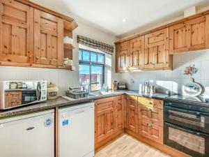 a kitchen with wooden cabinets and a white dishwasher at Betty Hutton - Uk36661 in Goulsby