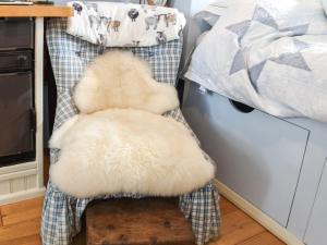 un animal de peluche sentado en una silla junto a una cama en Farmhouse Garden Shepherds Hut en Thursley