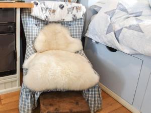 a stuffed animal sitting on a chair next to a bed at Farmhouse Garden Shepherds Hut in Thursley