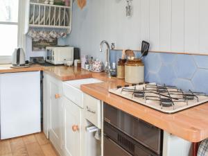 a kitchen with a stove top oven next to a counter at Farmhouse Garden Shepherds Hut in Thursley