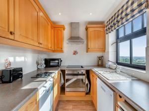 una cocina con armarios de madera y una gran ventana en Viking Cottage - Uk36662, en Goulsby
