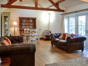 uma sala de estar com dois sofás de couro e uma mesa em Clover Hill Farm em Coanwood