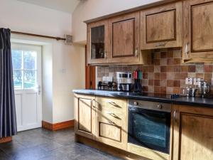 a kitchen with wooden cabinets and a black counter top at Clover Hill Farm in Coanwood