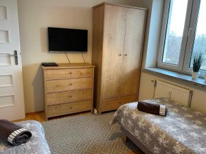 a bedroom with a television and a dresser with a dresser at Apartament Mieszka in Kołobrzeg