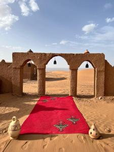 una manta roja sentada en medio del desierto en Bivouac Erg Chegaga Nomademoi, en El Gouera