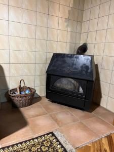 a black stove sitting on a tiled floor with a basket at Zelena oaza in Divčibare