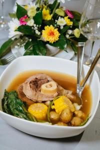- un bol de soupe avec de la viande, des légumes et des fleurs dans l'établissement El Bien Hotel Tagaytay, à Tagaytay